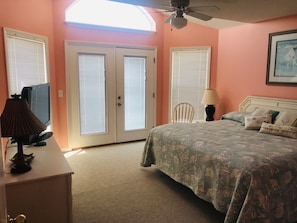 A bedroom with a bed, a desk, a chair, and a ceiling fan.