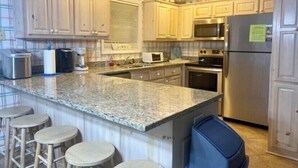 Una cocina con encimeras de granito, electrodomésticos de acero inoxidable y taburetes de madera.