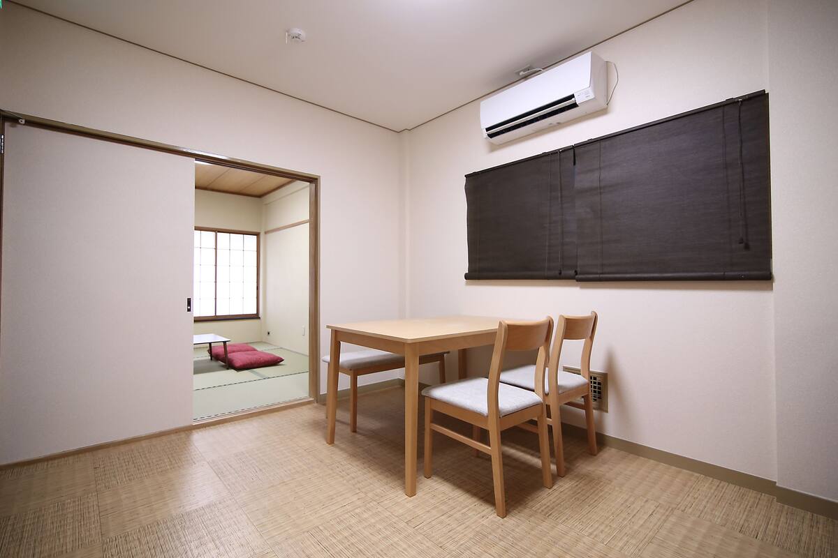 A room with a wooden table and chairs, a sliding door, and an air conditioning unit on the wall.