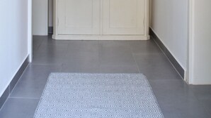 A hallway with a white cabinet, a decorative wall piece, and a patterned rug.
