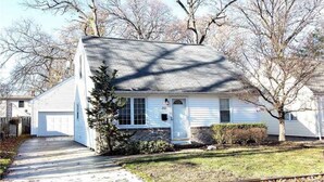 A single-story house with a front garage, a small front yard, and a tree casting a shadow on the house. - Relax close to the lakefront! Three bedroom Avon Lake retreat just steps away. (AVON LAKE)