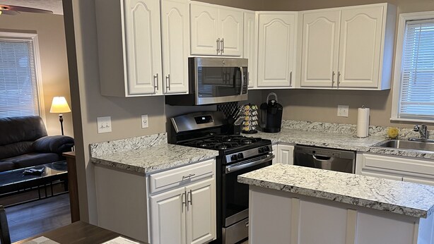 A modern kitchen with white cabinets, a stainless steel stove, and a granite countertop. - Relax close to the lakefront! Three bedroom Avon Lake retreat just steps away. (AVON LAKE)