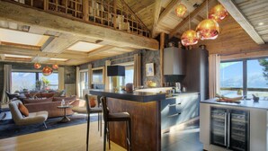 A modern kitchen with a central island, a dining area with chairs, and a living room with a sofa and a coffee table.