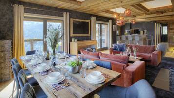 A dining area with a wooden table set for a meal, surrounded by sofas and chairs.