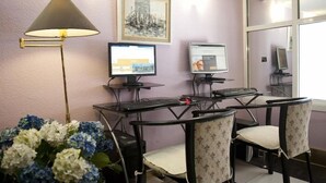 A computer desk with two monitors, a keyboard, and a mouse. There are two chairs, a lamp, and a framed picture on the wall. - Arha Santander (Santander)