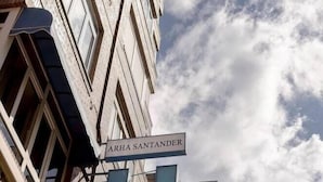 A multi-story building with a sign reading "ARHA SANTANDER" and a large blue 'H' sign. - Arha Santander (Santander)