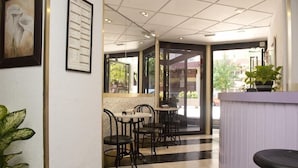 A hotel lobby with a check-in counter, several tables and chairs, and a large window offering a view of the outside. - Arha Santander (Santander)