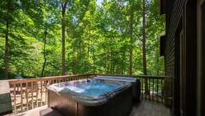 Una vasca idromassaggio su un pontile di legno con vista su una foresta.