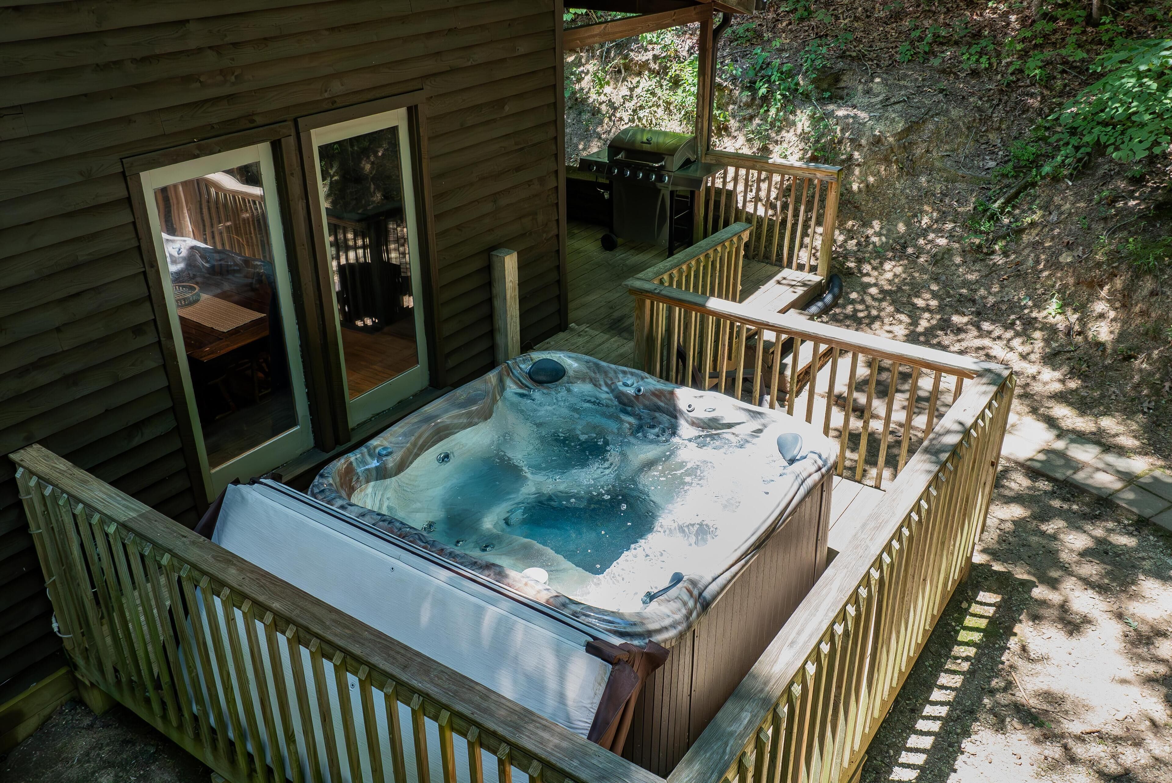 A hot tub in a wooden deck area with a view of a forested area.