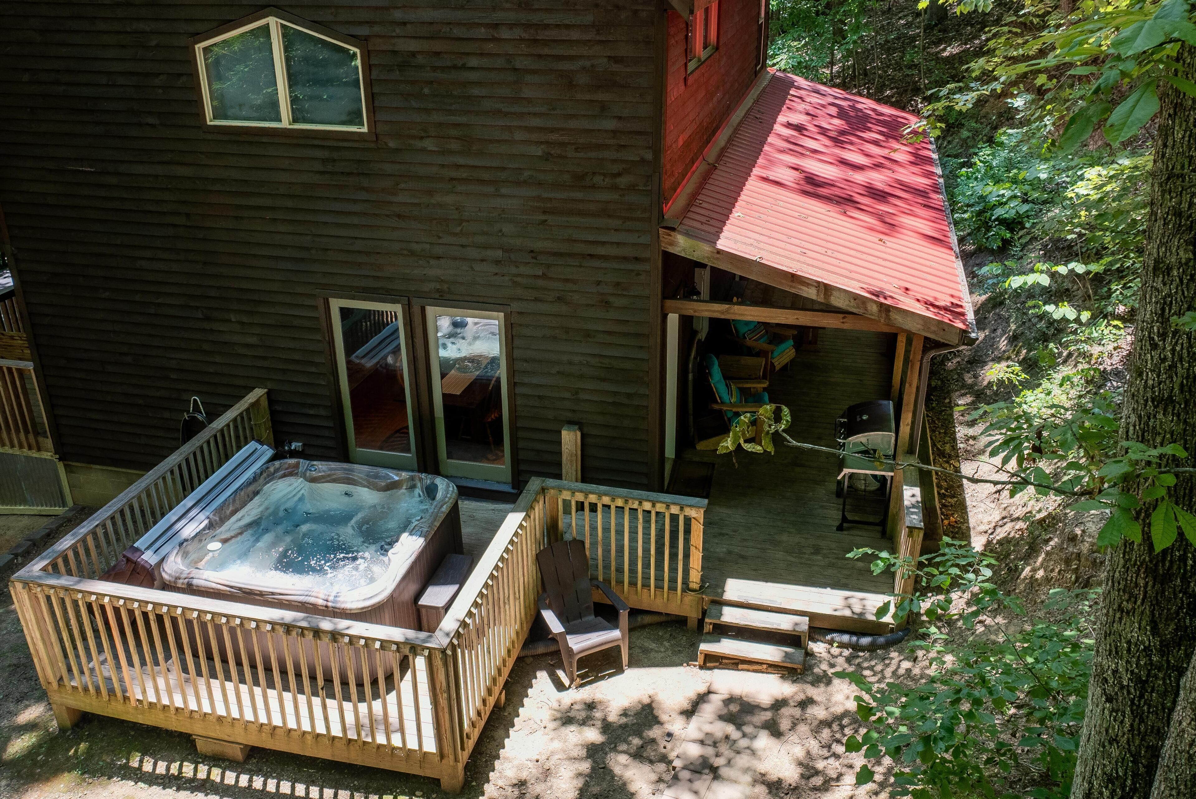A wooden cabin with a hot tub, deck chairs, and a covered outdoor seating area.