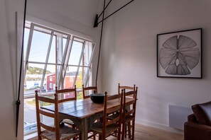 Ein Essbereich mit einem Holztisch und Stühlen, einer Schüssel auf dem Tisch und einem gerahmten Kunstwerk an der Wand.