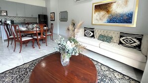 Ein modernes Wohnzimmer mit Essbereich, einem weißen Sofa und einem großen abstrakten Gemälde an der Wand.