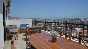 Ein Balkon mit Holztisch, Stühlen und einem Blumenvasen.