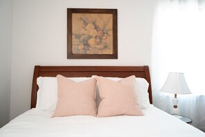 Restful retreat with a neatly made bed, framed artwork, and a bedside lamp.