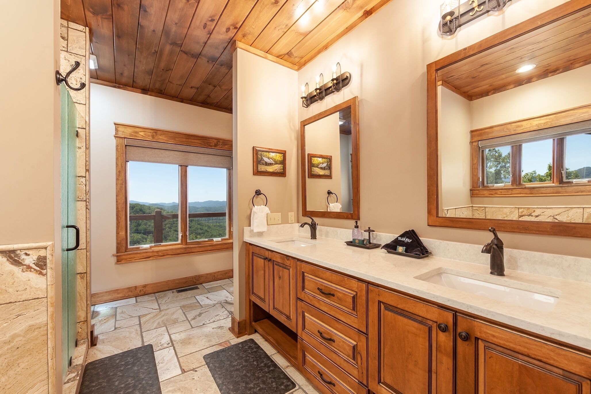 Un baño con armarios de madera, un espejo grande y una ventana con vistas al exterior.