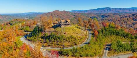 A large house surrounded by a winding road and autumn-colored trees.