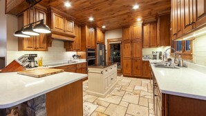 Una cocina con armarios de madera, una isla central y suelo de baldosas de piedra.
