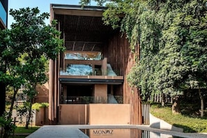 A modern building with a glass facade, wooden paneling, and a visible staircase leading to an upper level. - Monaz River Kwai Kanchanaburi (Kanchanaburi)