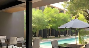 An outdoor seating area with a pool, surrounded by trees and a building. - Monaz River Kwai Kanchanaburi (Kanchanaburi)