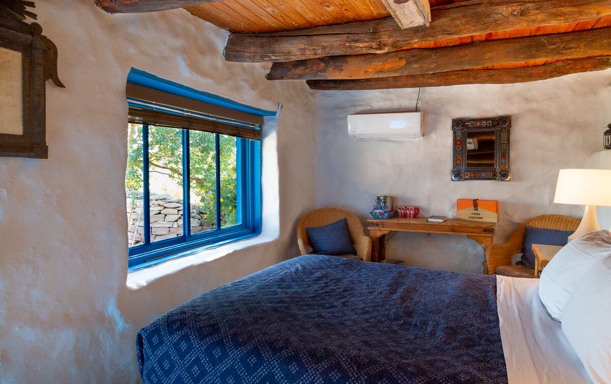 A rustic room with a bed, a desk, and a window.