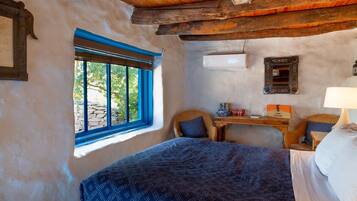 A rustic room with a bed, a desk, and a window.