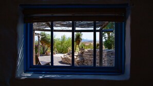Una ventana con vistas a un patio de piedra, una palmera y un paisaje desértico.