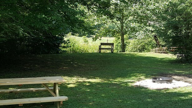 A picnic area with a bench and a fire pit.