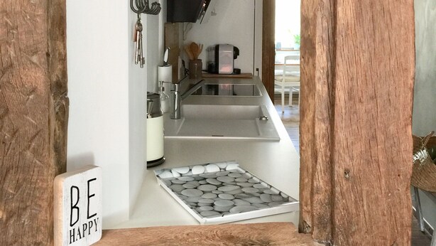 Une cuisine au design moderne, dotée d’un évier en acier inoxydable, d’une hotte noire et d’éléments décoratifs en bois.