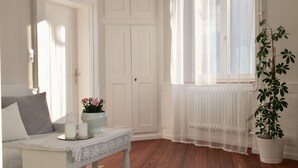 Une pièce avec un canapé blanc, un tapis à motifs, une table blanche ornée de bougies et une plante en pot.
