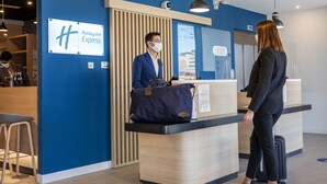 A Holiday Inn Express reception desk with a blue wall, a wooden counter, and a sign above it.