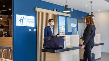 A Holiday Inn Express reception desk with a blue wall, a wooden counter, and a sign above it.