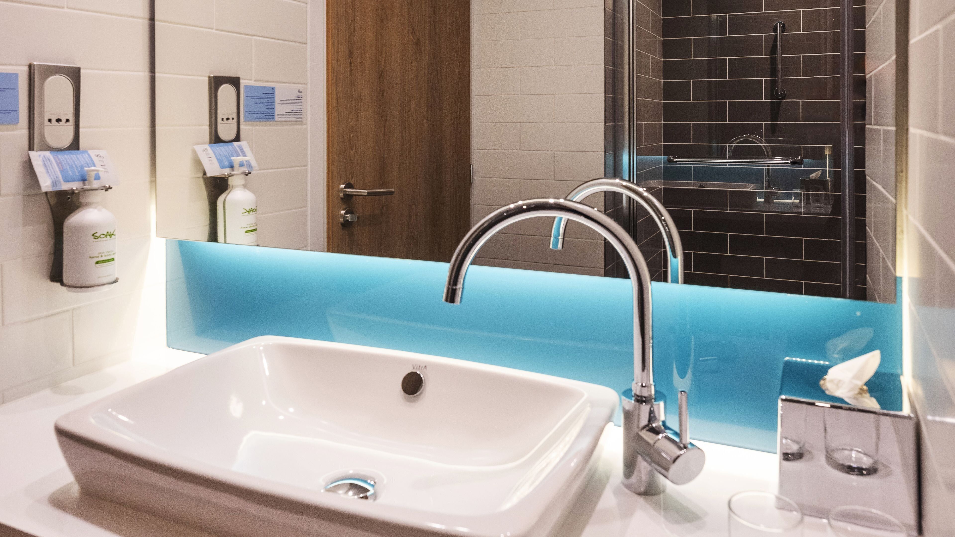 A modern bathroom with a white sink, chrome faucet, and a blue accent wall.