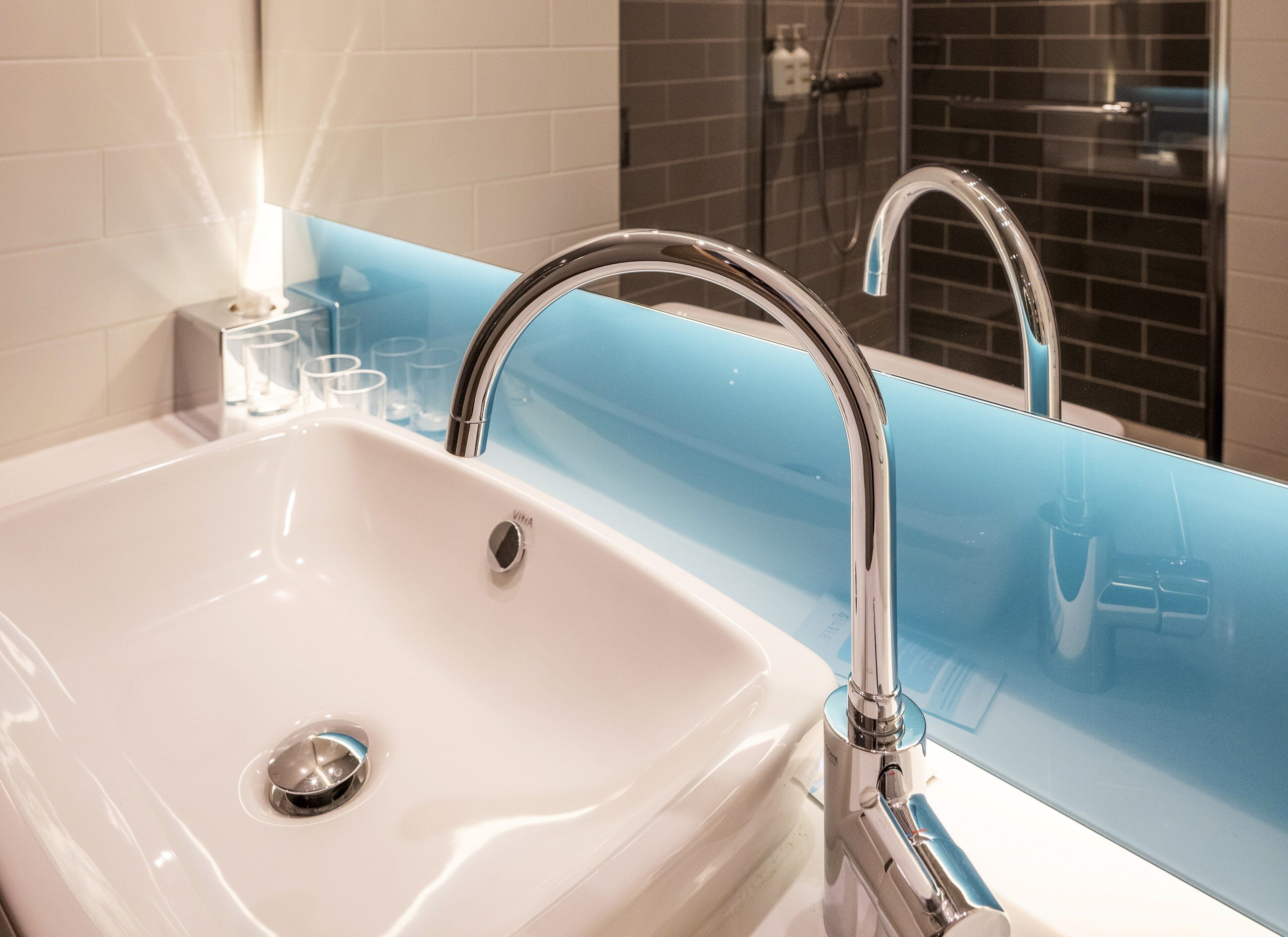 Une salle de bain avec un lavabo blanc, un robinet chromé et un plan de toilette bleu.