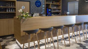 A modern bar area with a wooden counter, bar stools, and a variety of glassware.