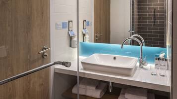 A modern bathroom with a glass shower enclosure, a white sink, and a blue accent wall.