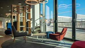 A modern interior with a seating area, large windows, and a view of the cityscape.