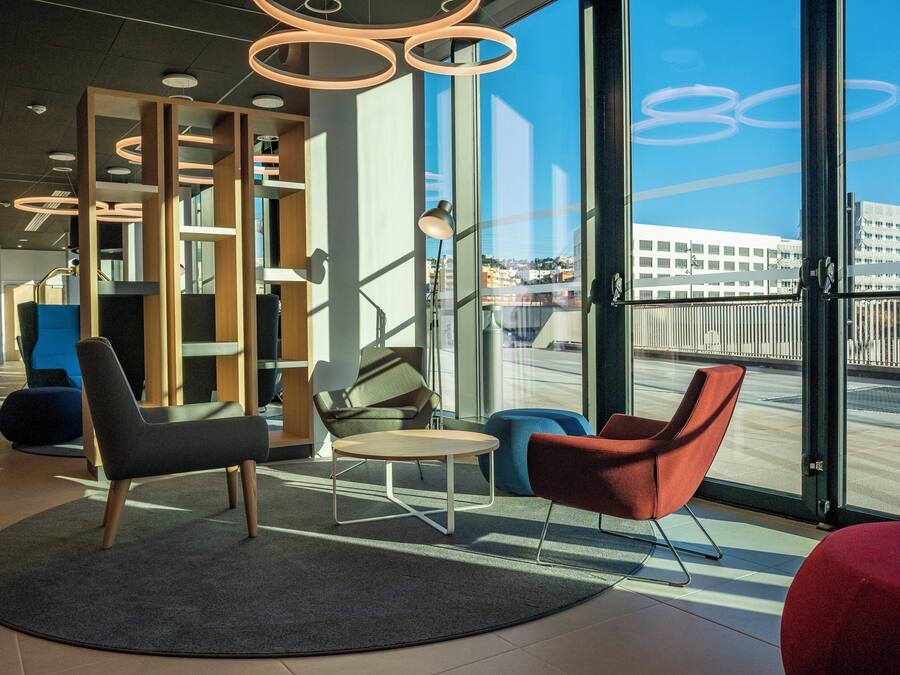 Een modern interieur met een zithoek, grote ramen en uitzicht op de stad.