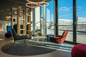 A modern interior with a seating area, large windows, and a view of the cityscape.