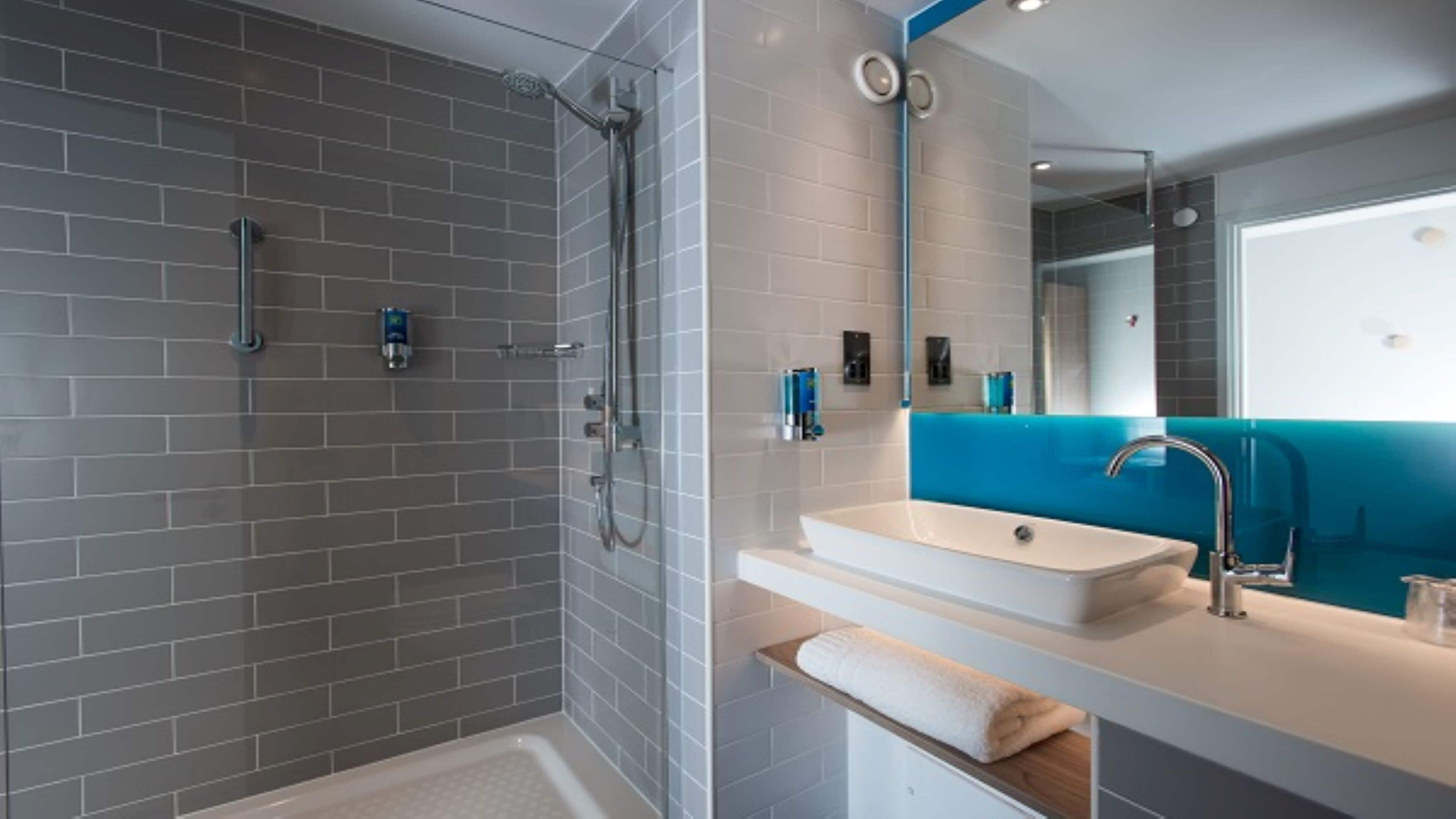 A modern bathroom with a shower, a sink, and a mirror.