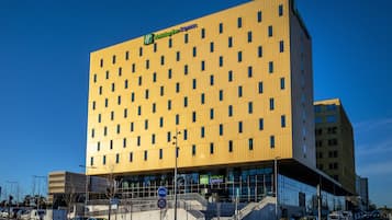 A modern Holiday Inn Express hotel with a yellow facade, large windows, and a visible entrance.