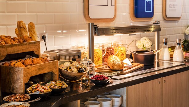 A buffet with various food items, including pastries, nuts, and a bread basket.
