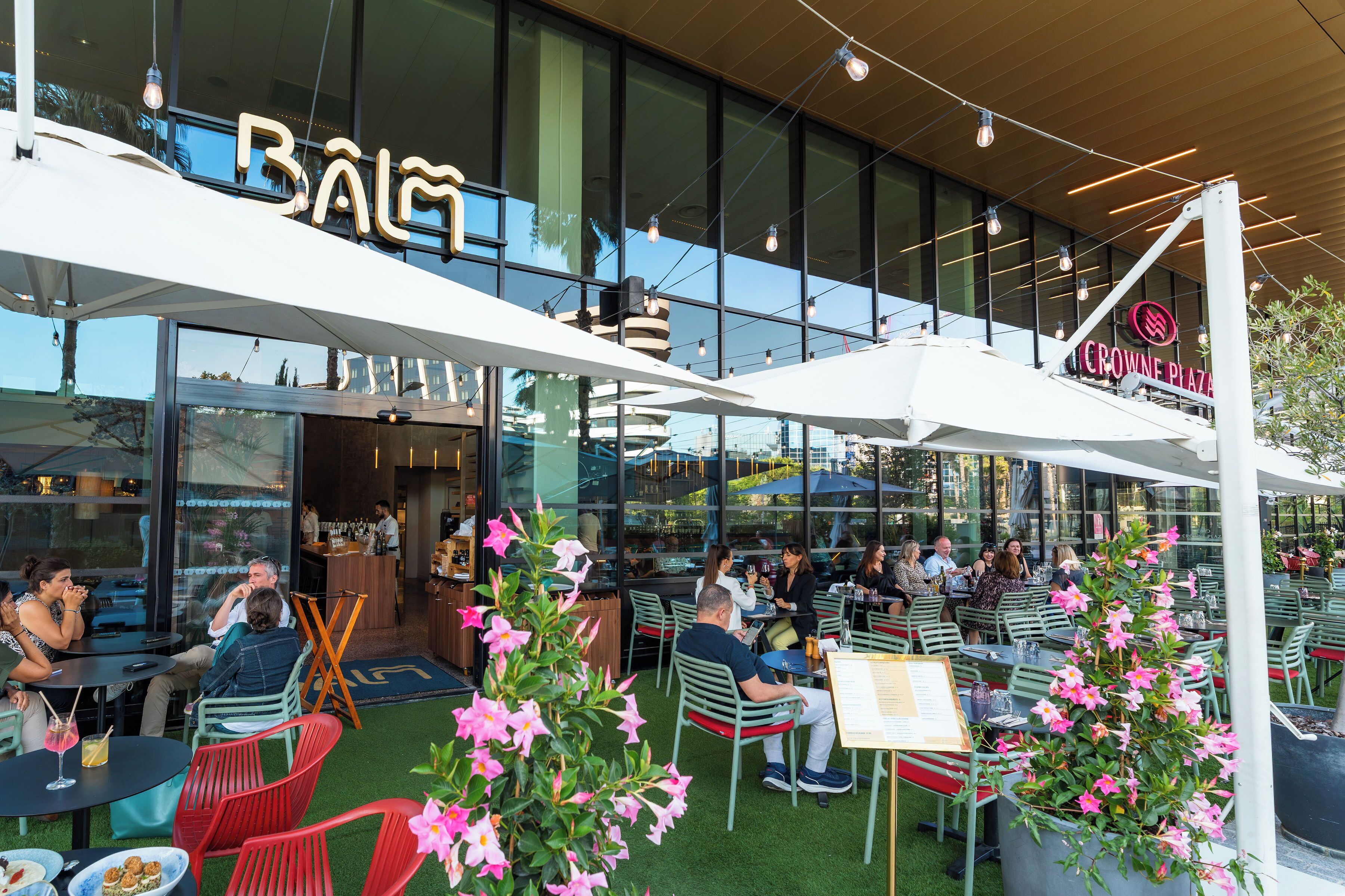 Un espace extérieur aménagé avec des tables et des chaises, un bar et une grande façade vitrée.