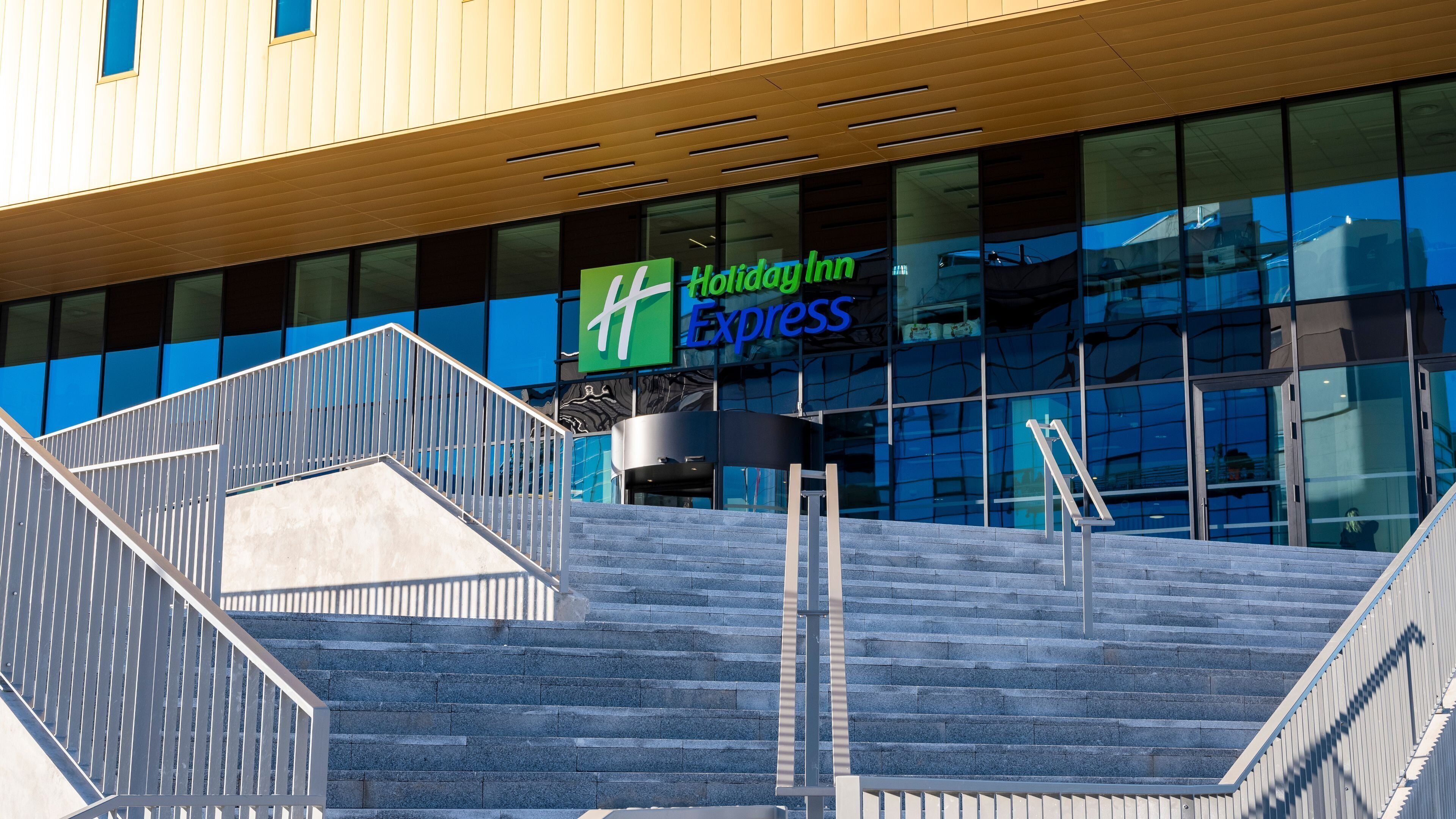 A staircase leading to a Holiday Inn Express building with a modern design and glass facade.