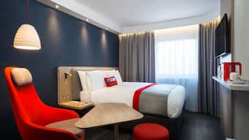 Ein Hotelzimmer mit einem Bett, einem Schreibtisch, einem Stuhl, einem Tisch und einer Pendelleuchte.