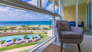 A room with a large window overlooking a pool and beach.