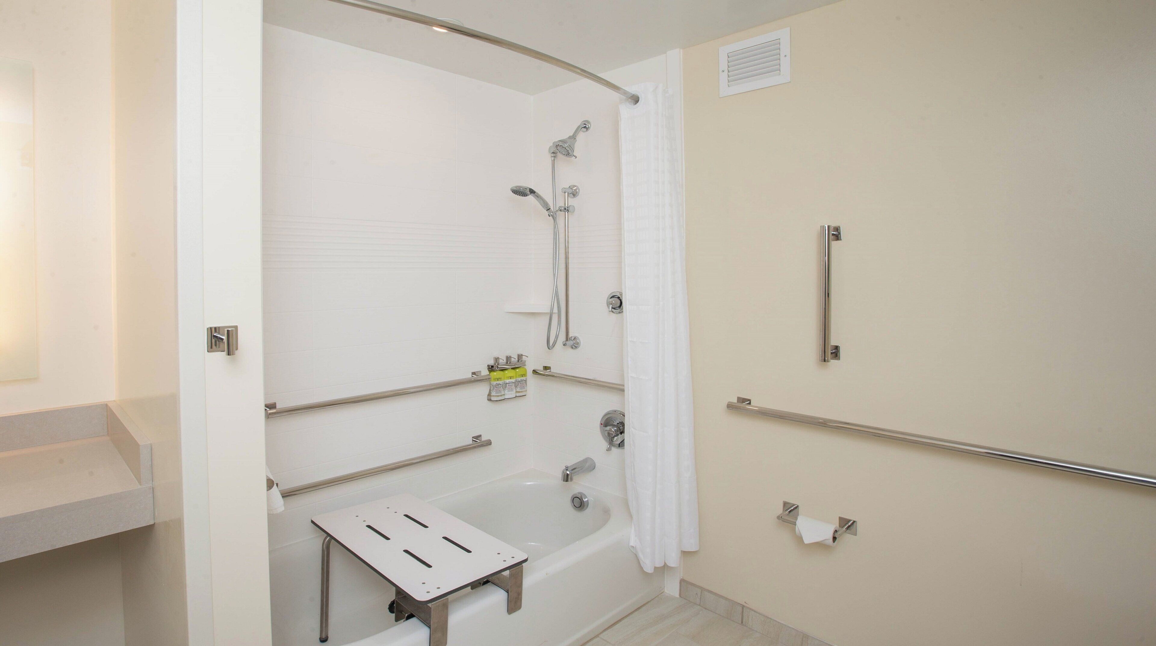 A bathroom with a bathtub, shower, and grab bars.