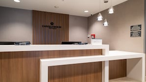 Un comptoir d’accueil avec un panneau décoratif en bois, une enseigne pour Candlewood Suites et un kiosque numérique.