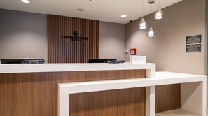 A reception desk with a wooden panel design, a sign for Candlewood Suites, and a digital kiosk.