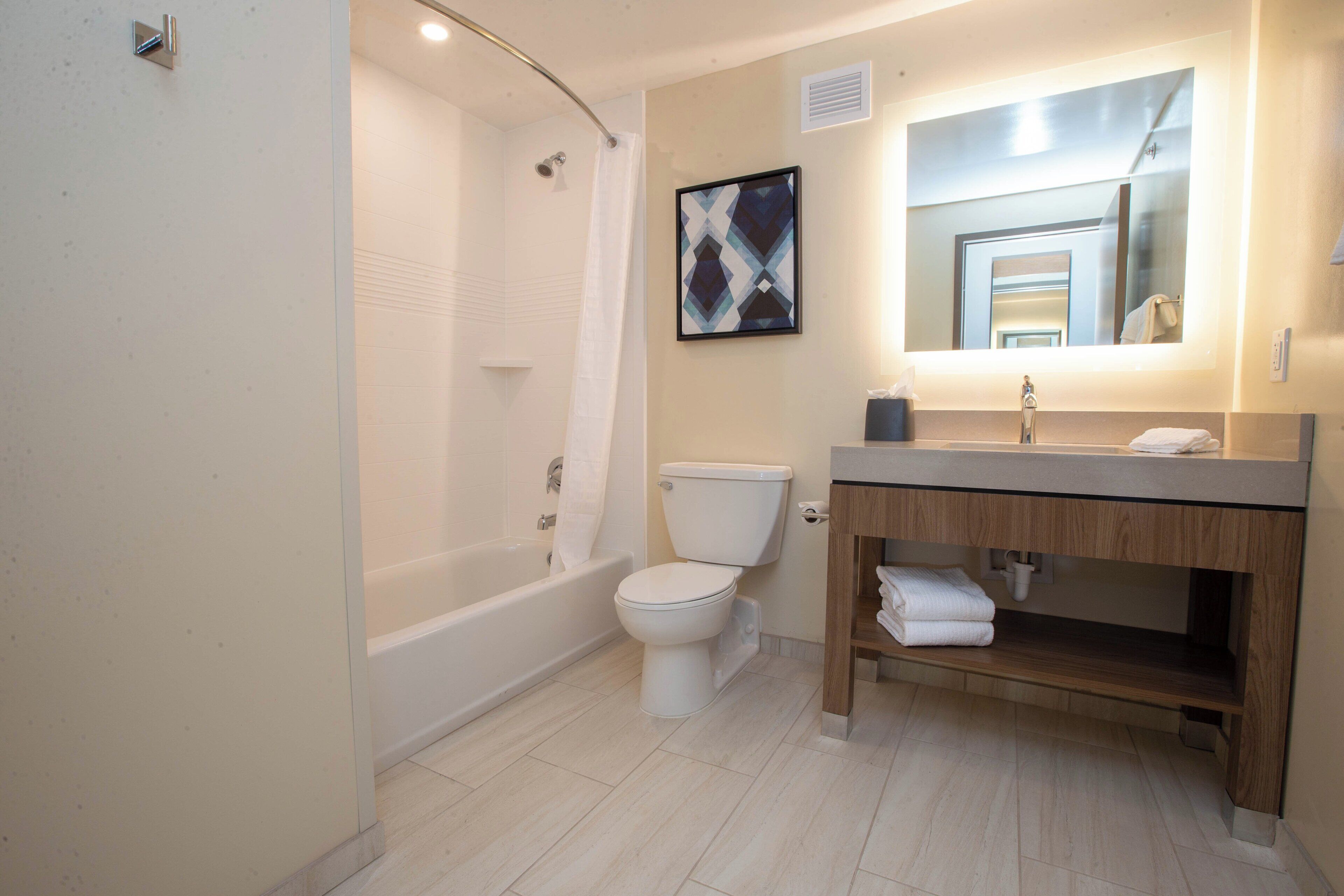 A modern bathroom with a bathtub, toilet, and vanity.
