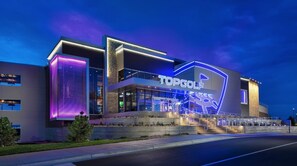 Un bâtiment moderne, reconnaissable à son grand panneau « TOPGOLF », à ses larges baies vitrées et à son entrée bien éclairée.